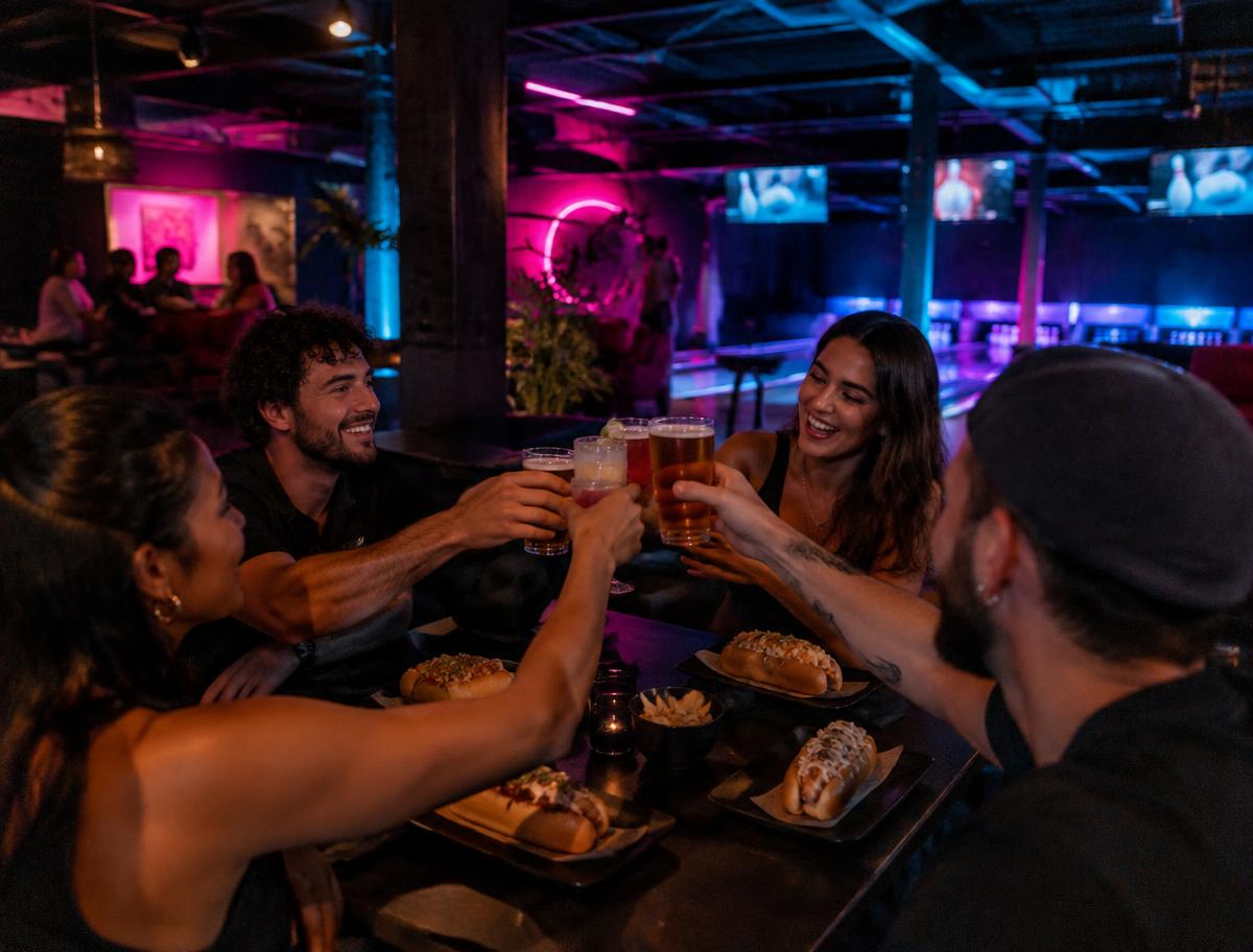 Amigos brindando y riendo alrededor de una mesa en HOTLAB